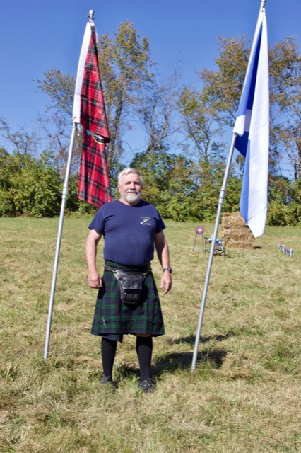 Highland Games participant standing between Scottish flags