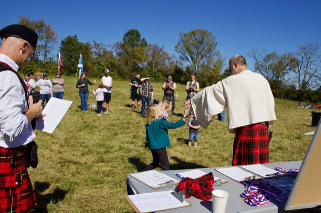 Child receiving a Highland Games medal at the awards table